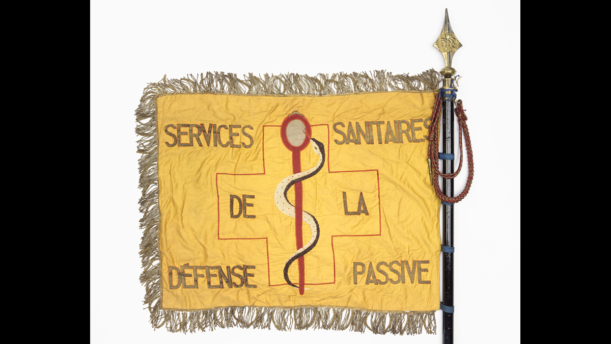Drapeau des services sanitaires de la défense passive (Paris et département de la Seine) - L’organisation des services sanitaires fait partie de l’ensemble des mesures de défense passive. On y compte les services de soins aux victimes des bombardements aériens, les services de détection et les services de désinfection. / Paris, musée de l'Armée, inv. 2017.19.1 © Paris - Musée de l'Armée, Dist. RMN-Grand Palais / Emilie Cambier