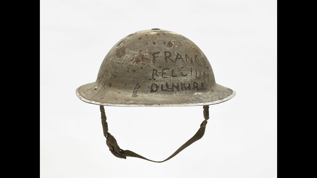 Casque britannique mark II - Le soldat à qui appartenait ce casque, considéré comme un souvenir de ses campagnes en 1940, a gravé les noms des deux pays dans lesquels il s’est battu et celui de la ville de Dunkerque, où il fut réembarqué. / collection particulière © Paris - Musée de l'Armée, Dist. RMN-Grand Palais / Emilie Cambier