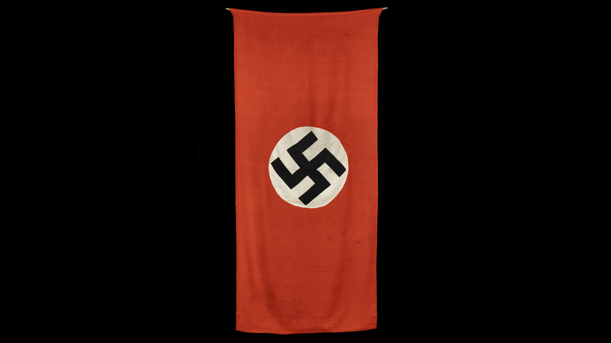 Pavillon allemand - Sur tous les édifices publics de la zone occupée, les Allemands déploient symboliquement  le drapeau à croix gammée. Celui-ci a été pris à la citadelle de Belfort le 20 novembre 1944 par Jean Lartéguy, alors jeune sous-officier et futur correspondant de guerre  et romancier. / Paris, musée de l'Armée, inv. 21696 © Paris - Musée de l'Armée, Dist. RMN-Grand Palais / Emilie Cambier