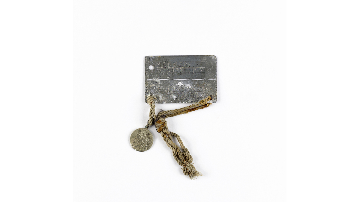 Plaque d’identité de prisonnier de guerre et médaillon religieux du soldat de 2e classe Franciszek Zdunek, 1re division de grenadiers polonaise - Symbole de captivité pour plus d’un million de soldats alliés, ces plaques furent portées par l’ensemble des prisonniers de guerre. Sur la plaque figure le type du camp, Frontstalag pour les camps situés en France, Oflag pour les camps d’officiers situés en Allemagne et Stalag pour la troupe, ainsi que le numéro du camp et le numéro de matricule attribué au soldat. Sur l’une d’entre elles, un petit médaillon religieux a été agrémenté par son propriétaire (soldat polonais). / Collection privée © Paris - Musée de l'Armée, Dist. RMN-Grand Palais / Anne-Sylvaine Marre-Noël