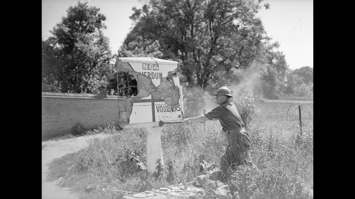 13-31 mai. Soldat français détruisant un panneau indicateur afin de perturber l'avancée allemande dans le secteur des 2e et 4e armées, entre l'Aisne et la Meuse. / © Photographe inconnu/SCA : Service Cinématographique des Armées/ECPAD/Défense/DG 109 - 1379